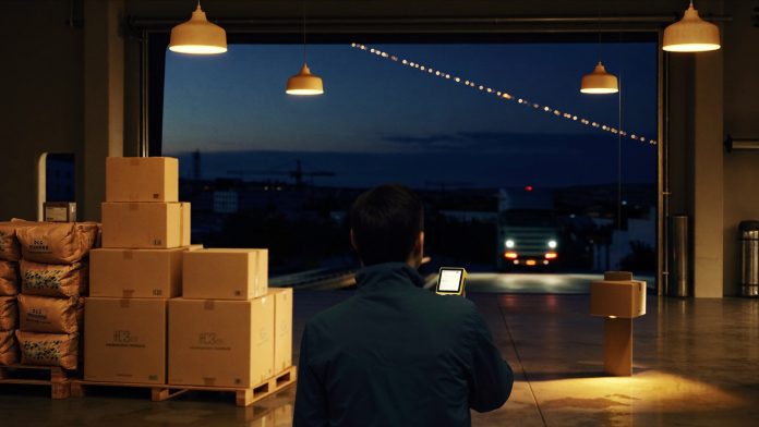 Pets Deli und VAFO: Logistiklager in der blauen Stunde Fulfilment-Lager in der Dämmerung: Paletten mit Kartons und Futtersäcken, warme Lampen, ein abfahrender Lkw – Sinnbild für die Übernahme des Berliner D2C-Startups Pets Deli durch die tschechische VAFO Group.